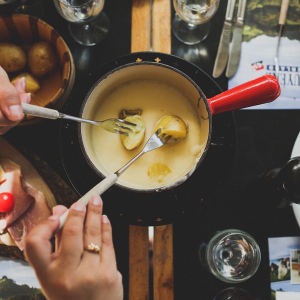 two person holding fork dipping food on sauce